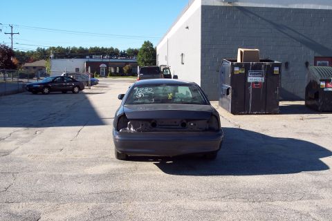 2001 Ford Crown Victoria - Rear view of a dark sedan, identified as Unit #1832, with its taillights and bumper removed.