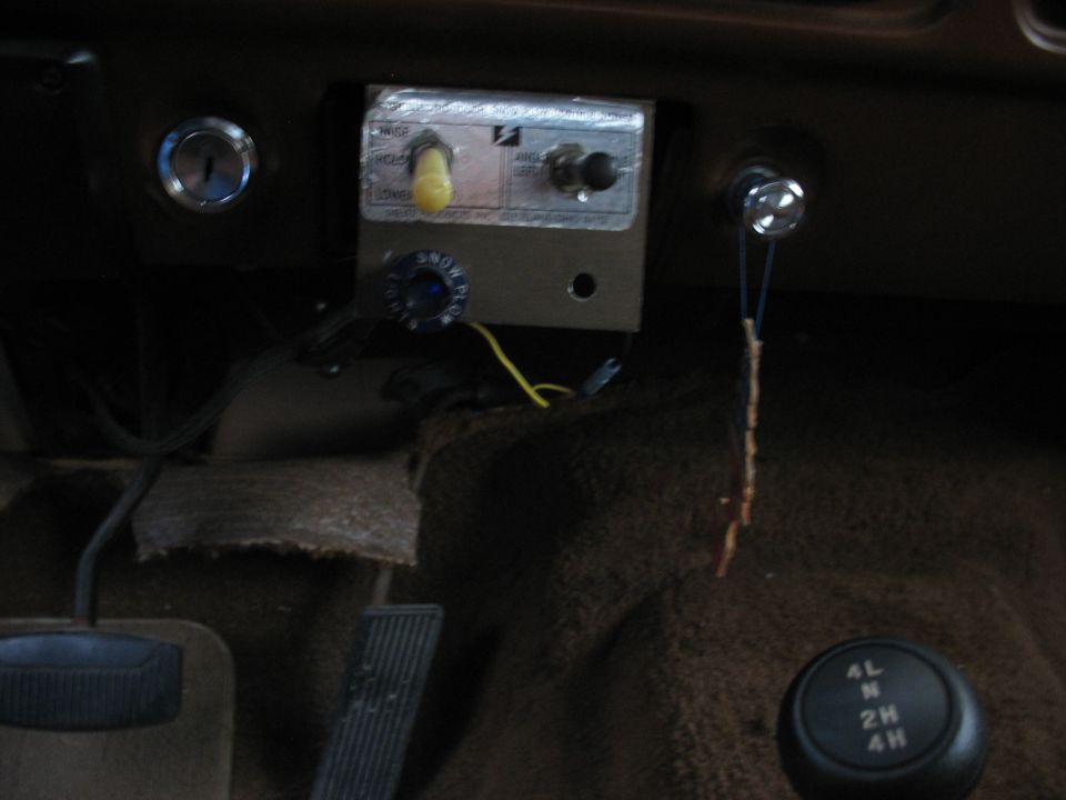 Interior shot of a vehicle's dashboard with a custom control panel, ignition, and a 4x4 gear shifter