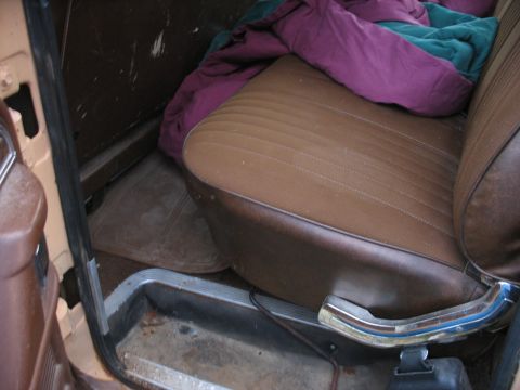 1978 Ford F-250 - Interior view of a truck's passenger seat, covered with blankets, showing the door sill and floor mat.