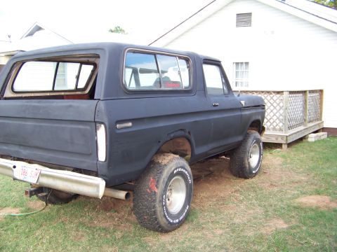 1979 Ford Bronco - This black Ford Bronco is shown from the rear 3/4 angle, parked on grass.