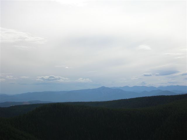 Layered blue mountains under a hazy sky with scattered clouds