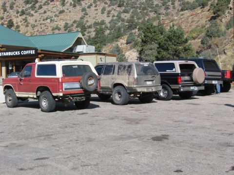 1996 Ford Bronco - A red and white 1980s Ford Bronco is parked in front of a Starbucks with a spare tire mounted on the rear. Behind it are three other SUVs p…