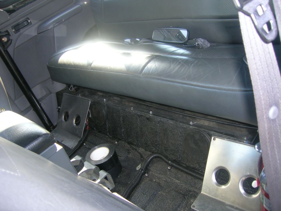 Gray rear bench seat above a bedlined cargo floor with custom aluminum panels