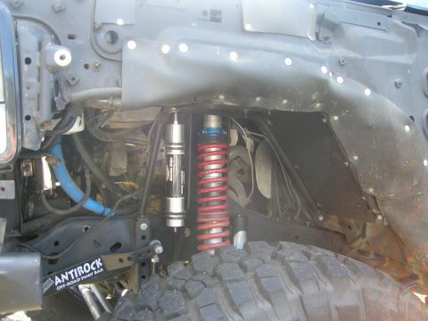 1996 Ford Bronco - The front driver-side wheel well of a modified 1996 Ford Bronco shows a red coilover shock absorber and a black sway bar with "ANTiROCK OFF…