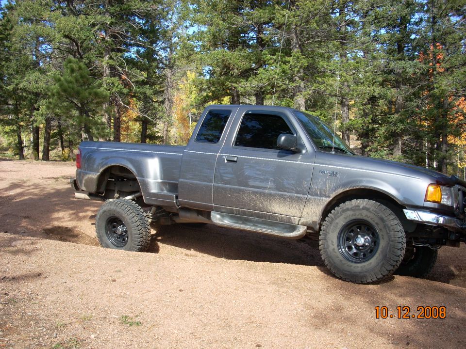 Gray lifted Ford Ranger pickup truck stuck in dirt off-road.