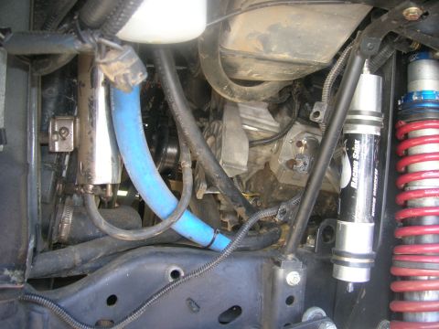 1996 Ford Bronco - A close-up view of the engine bay of a 1996 Ford Bronco shows various components including a blue hose, a silver filter, and a racing shock…