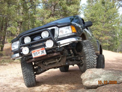 2004 Ford Ranger - This black 2004 Ford Ranger pickup truck is shown navigating a rocky off-road trail with its front tire on a large boulder.
