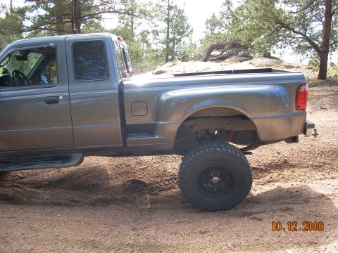 2004 Ford Ranger - This lifted Ford Ranger is parked off-road with a wooded area behind it.