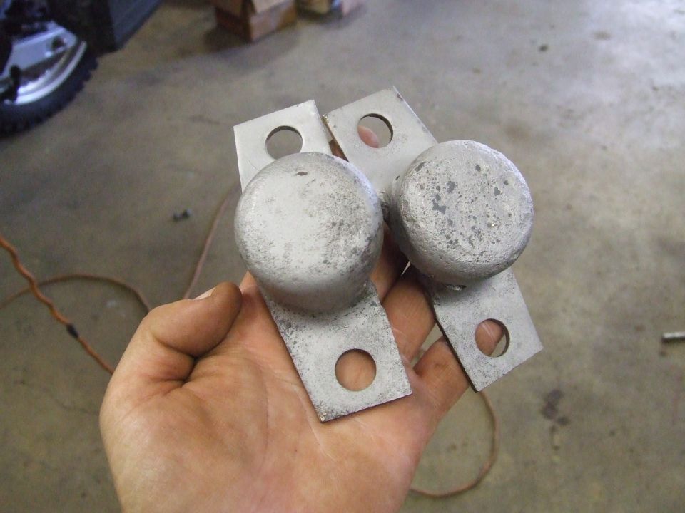 Two metal parts with round ends and mounting holes.