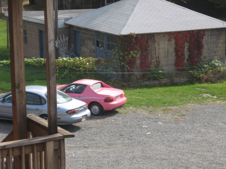Silver sedan and pink sports car parked in front of a stone building.