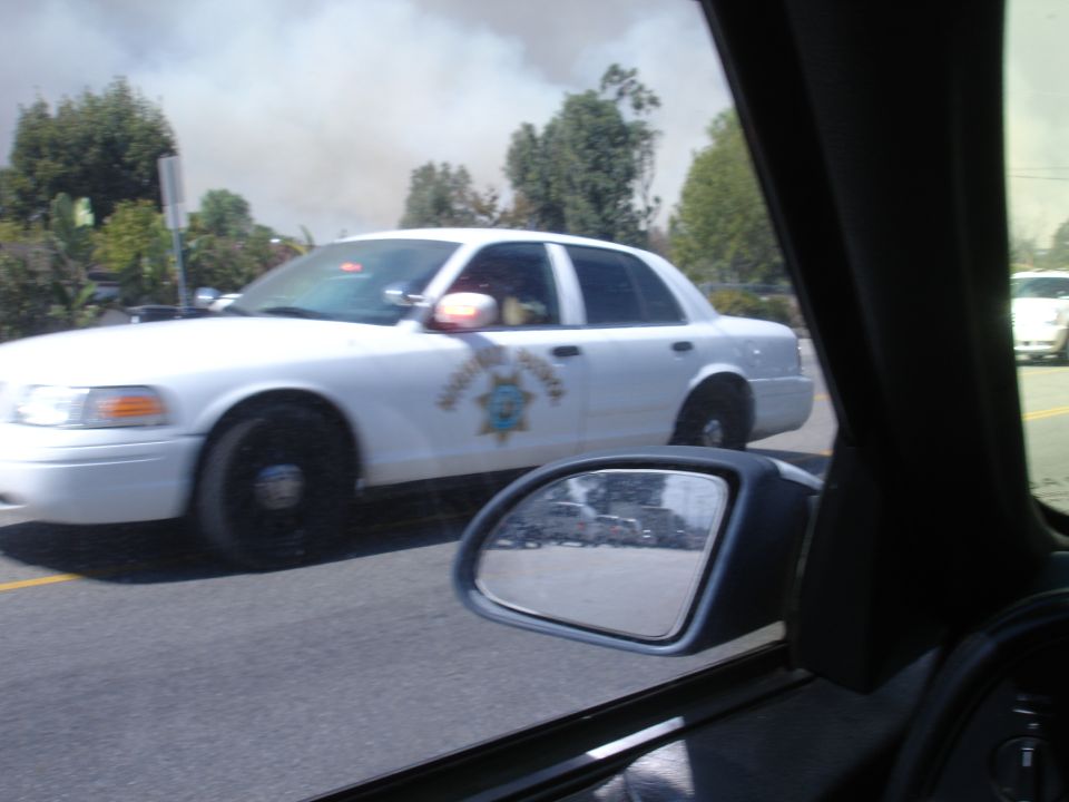 White California Highway Patrol sedan driving on a road, seen from passenger side.