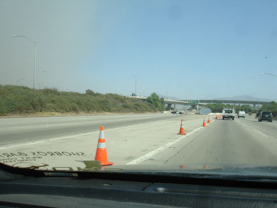 Highway scene with traffic cones, police car, and smoke.