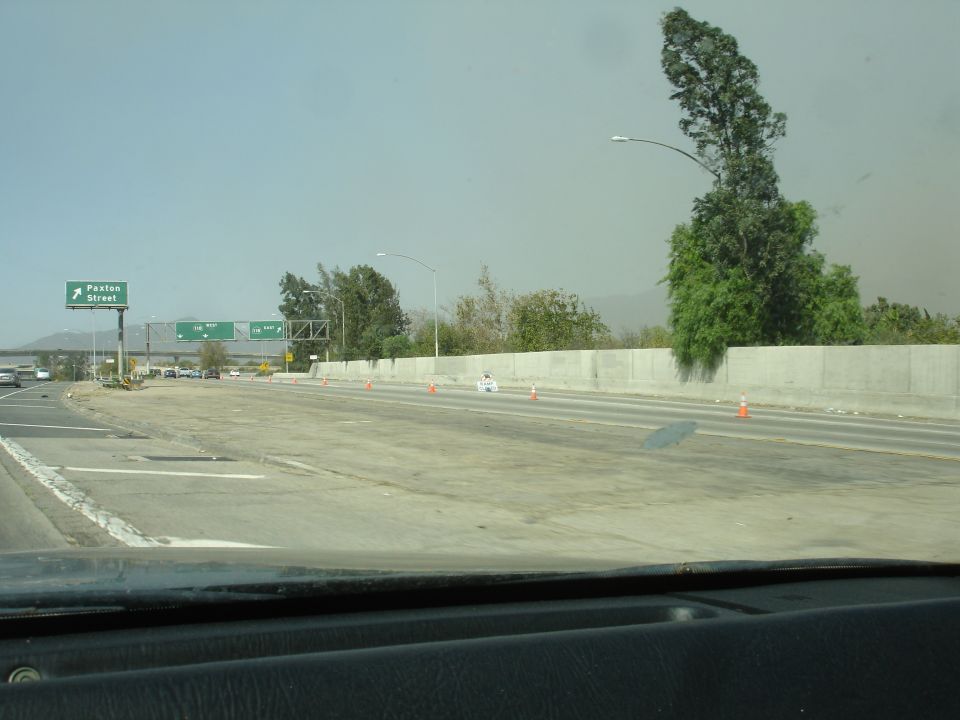 Highway scene with directional signs and a vehicle dashboard in the foreground.