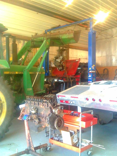 1992 Ford Bronco - A workshop scene with an engine on a stand, a tractor, a car on a lift, and a trailer.