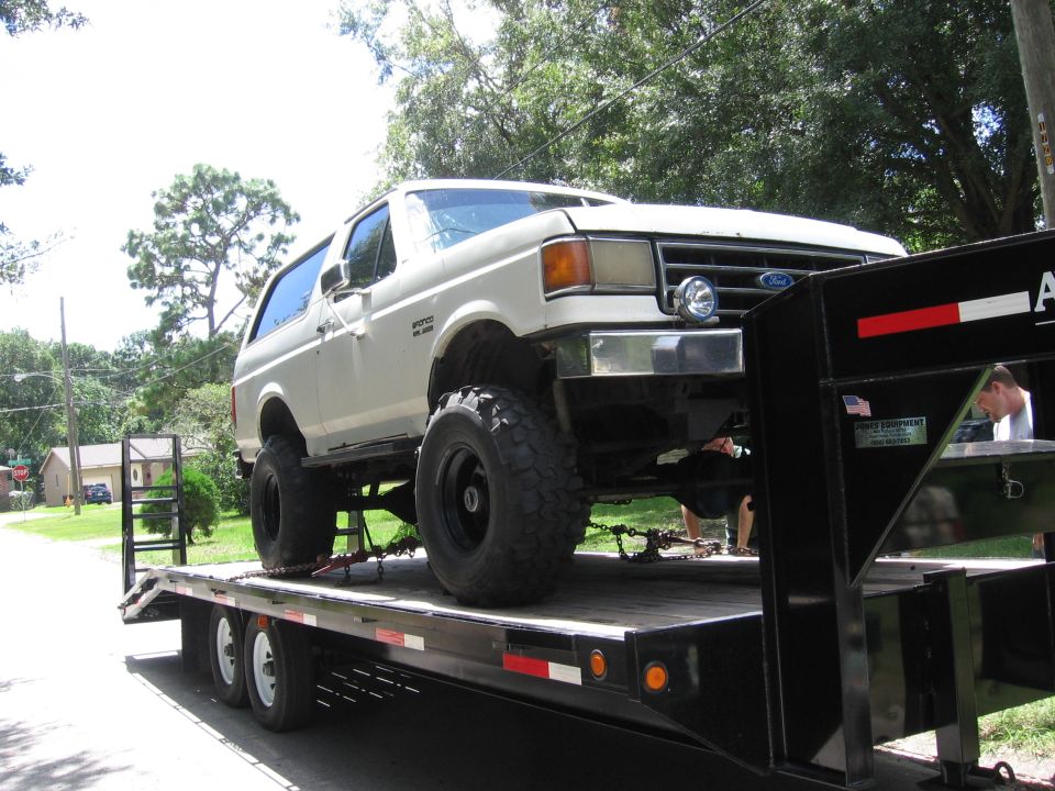 White Ford Bronco on a black flatbed trailer