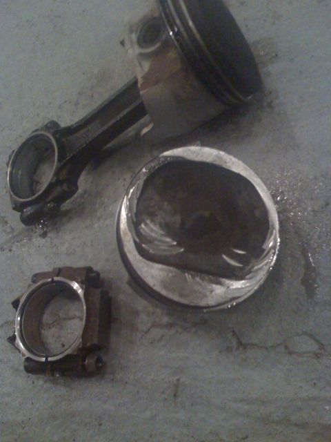 1992 Ford Bronco - Photograph of an engine piston and connecting rod laid on the floor, not a technical document.