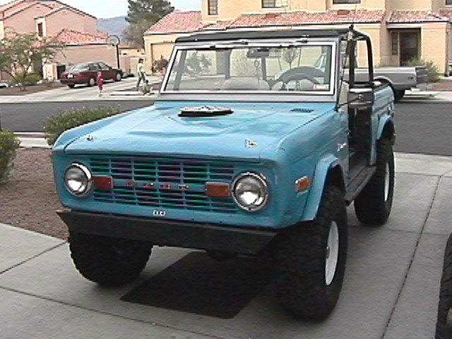 Turquoise early Ford Bronco with doors and top removed on a driveway