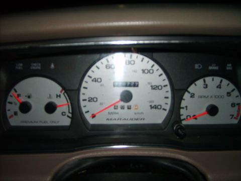 1993 Ford Crown Victoria - Close-up of an instrument cluster with a tan interior surround, showing a fuel/temperature gauge on the left, a central speedometer marked…