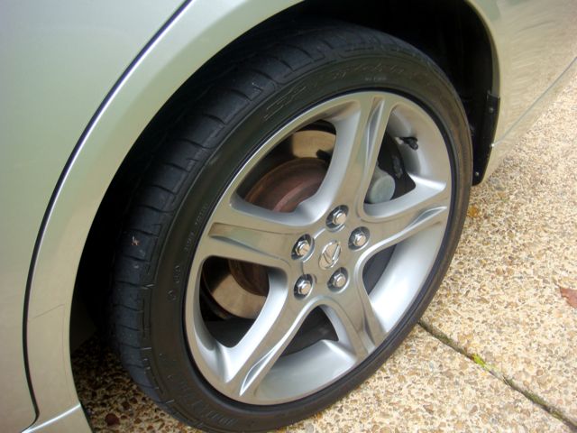 Close-up of a silver five-spoke alloy wheel and low-profile tire on a champagne-colored car