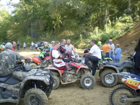 1997 Jeep Wrangler - A group of people in riding gear are gathered around several ATVs and dirt bikes in a muddy outdoor setting with trees in the background.
