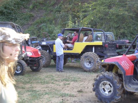 1997 Jeep Wrangler - Off-road vehicles gathered on a dirt area with people present. Text is visible on the red ATV.