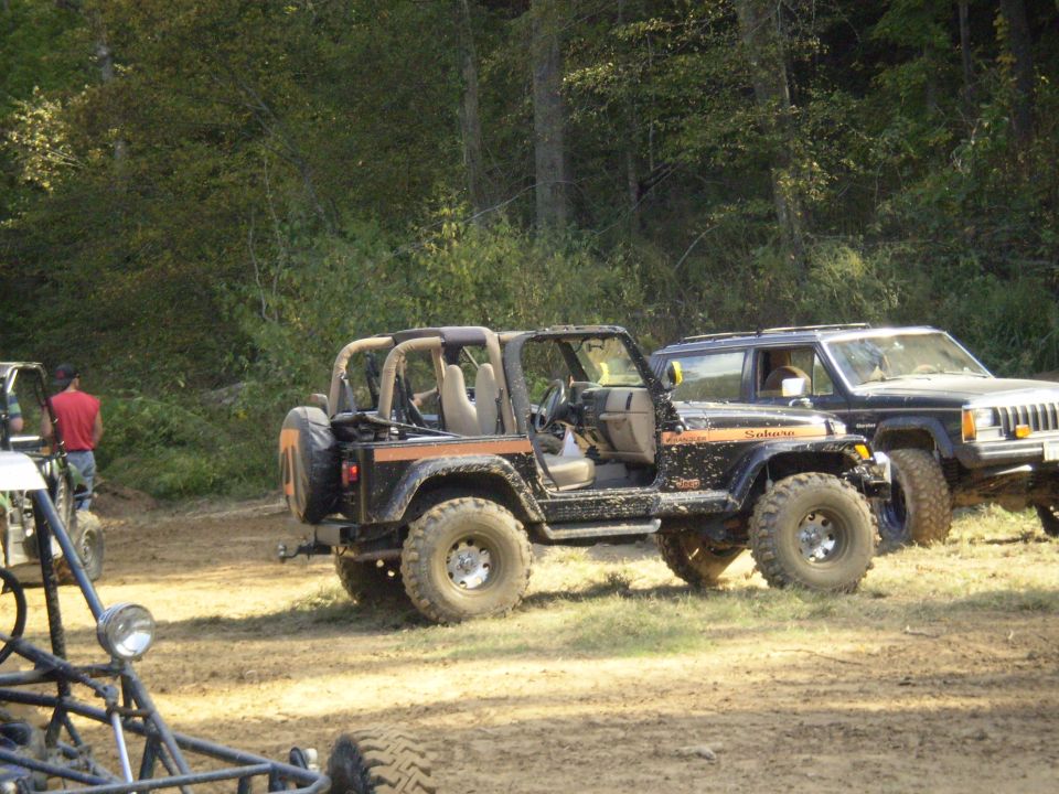 Black 1997 Jeep Wrangler with orange stripe, parked off-road