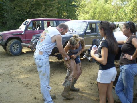 1997 Jeep Wrangler - A group of people are gathered around a muddy woman and two off-road vehicles in a wooded area.