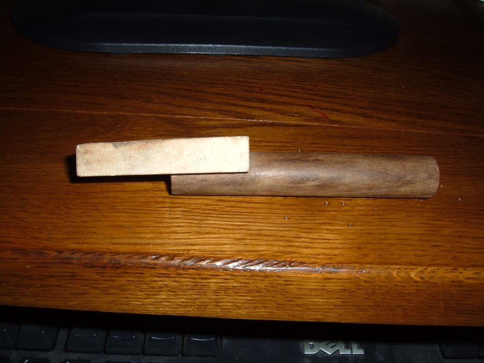 Wooden dowel with a rectangular block attached to one end, resting on a wooden surface