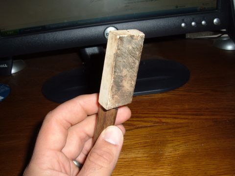 1998 BMW R1100GS ABS - A hand holds a sharpening stone with a wooden handle, resting on a wooden desk.