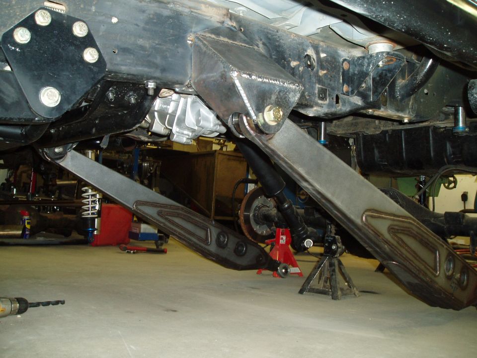 Custom suspension links and frame modifications under a vehicle, with a transmission visible