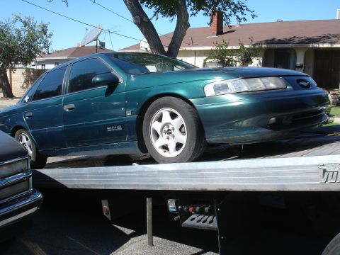 1993 Ford Taurus - A green sedan, identified as an Acura, is loaded onto a flatbed truck.