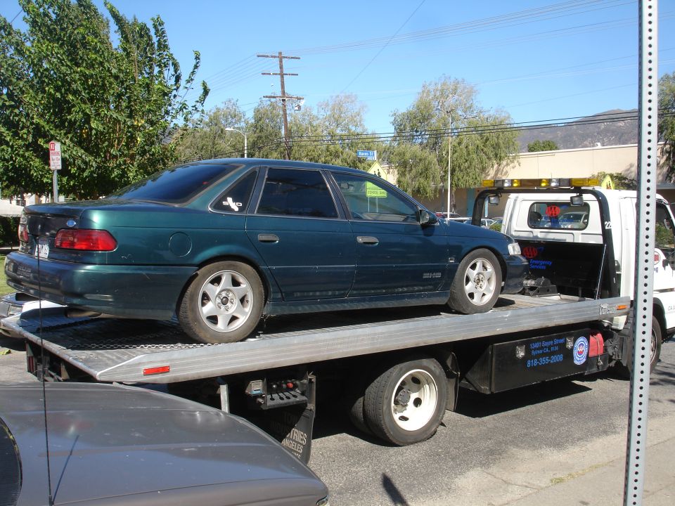 Dark green 1993 Ford Taurus sedan on a tow truck