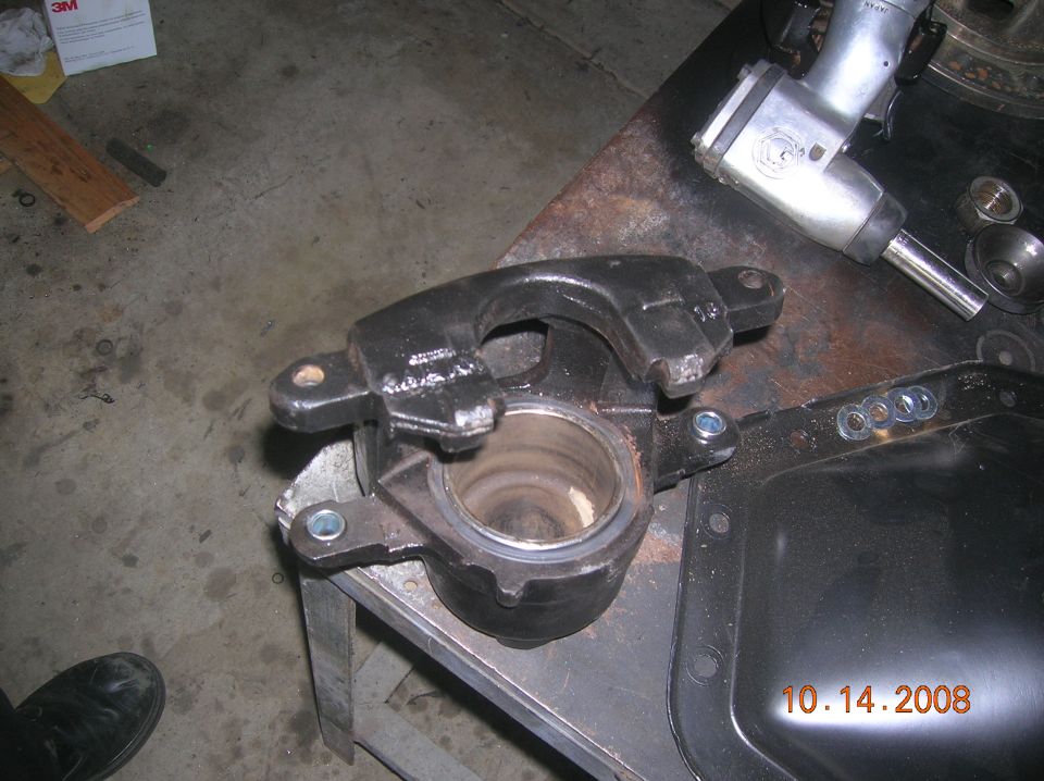 Black brake caliper and differential cover on a workbench with an impact wrench