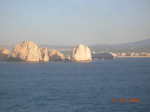 1985 Ford Bronco - A cruise ship is visible near a town and rock formations by the sea.