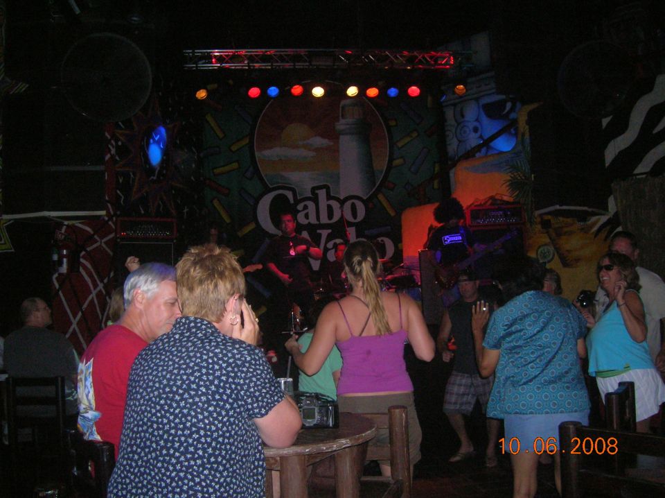People dancing at a concert venue with "Cabo" logo on stage