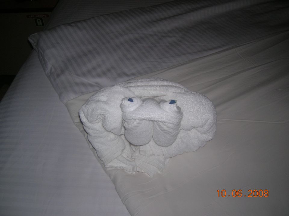 White towel folded into a crab shape on a bed with blue eyes