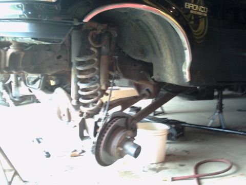 1996 Ford Bronco - The front suspension and brake components of a vehicle are visible, suggesting maintenance or repair work is underway.