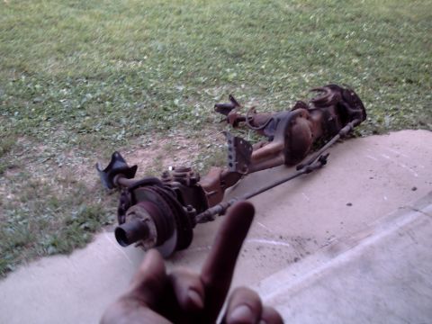 1996 Ford Bronco - A disassembled front axle assembly rests on a concrete pad next to a grassy area.