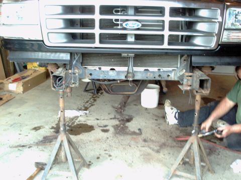 1996 Ford Bronco - Front end of a Ford truck is elevated on jack stands, revealing the radiator and front suspension components.