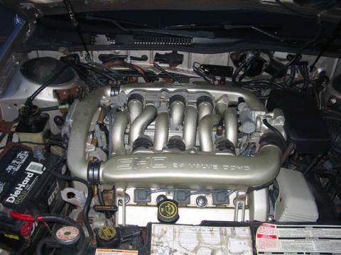 1990 Ford Taurus - The engine bay of a 1990 Ford Taurus SHO is visible, the V6 engine and a DieHard battery.