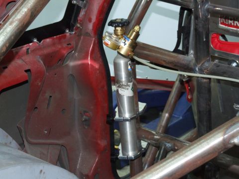 1990 Ford Mustang - A CO2 tank is mounted inside a car's interior, surrounded by a roll cage and red metal framing.