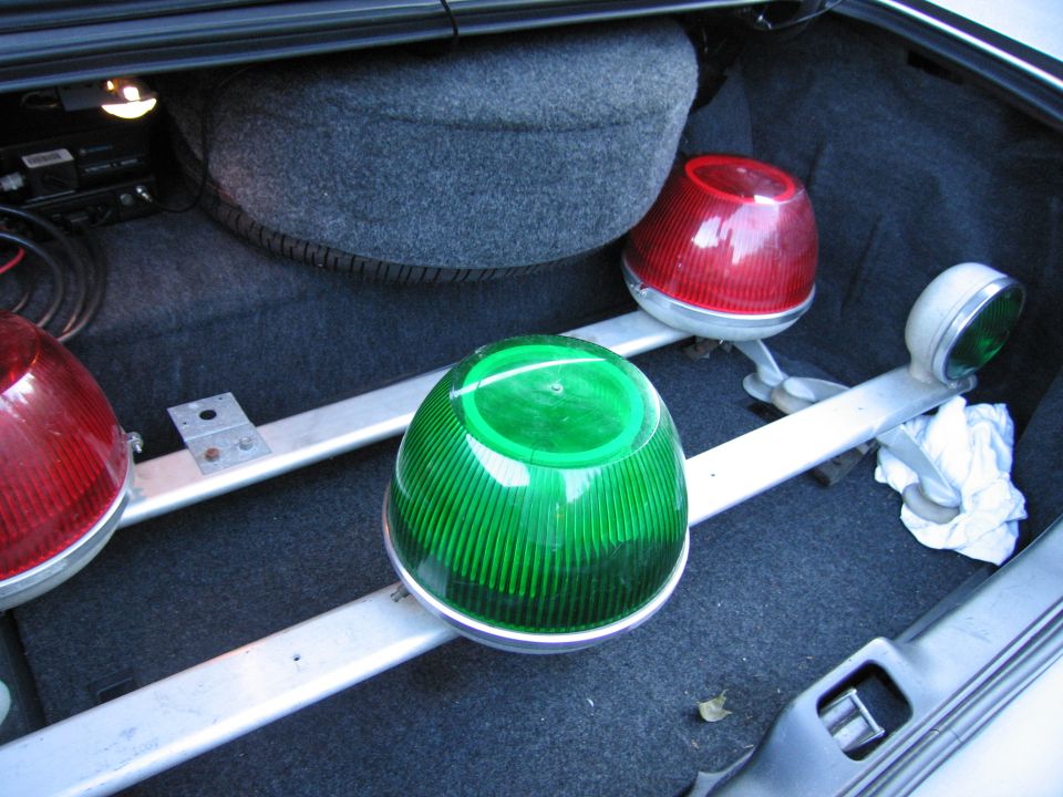 Trunk interior with spare tire, red and green emergency lights mounted on metal bars
