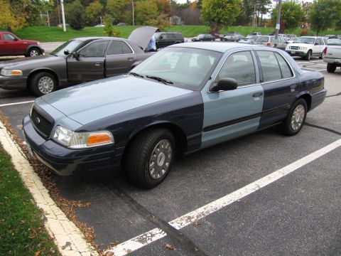2001 Ford Crown Victoria - A two-tone Ford Crown Victoria is parked next to another Crown Victoria in a parking lot.