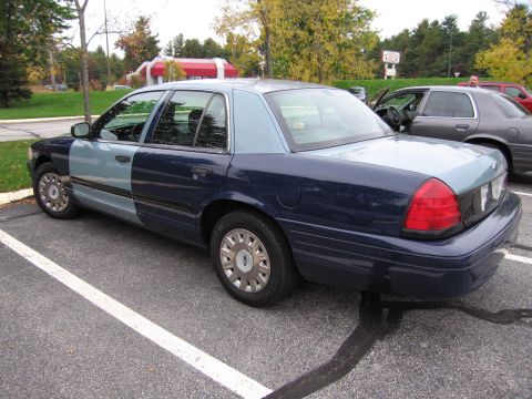 2001 Ford Crown Victoria - A sedan with mismatched paint colors is parked in a lot, with another vehicle visible behind it.