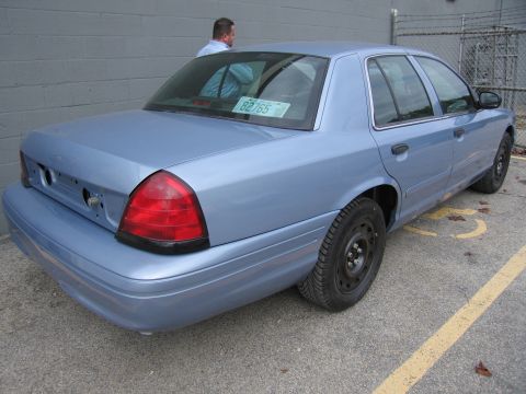 2001 Ford Crown Victoria - A light blue 2001 Ford Crown Victoria sedan is parked in a lot, viewed from the rear.