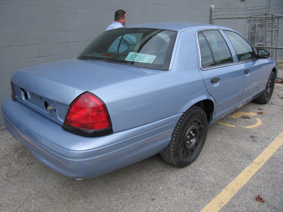 Light blue 2001 Ford Crown Victoria sedan, rear view, missing license plate holder, parked in a lot