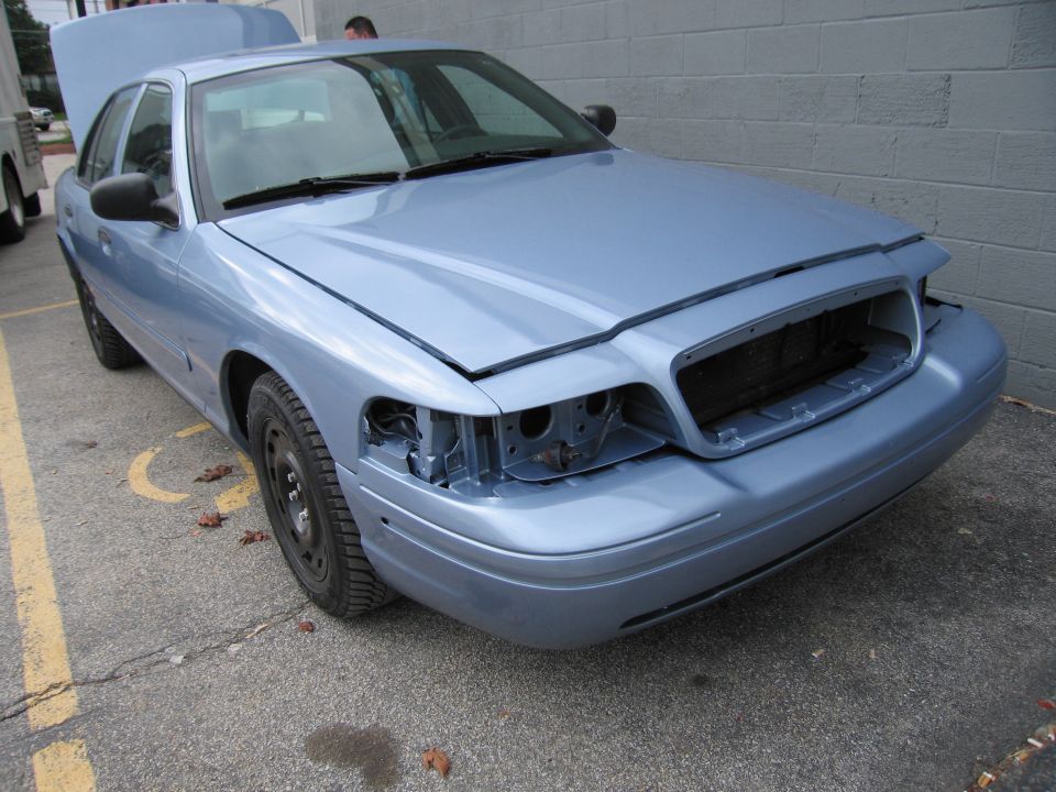 Light blue 2001 Ford Crown Victoria, front missing headlights, hood and trunk open