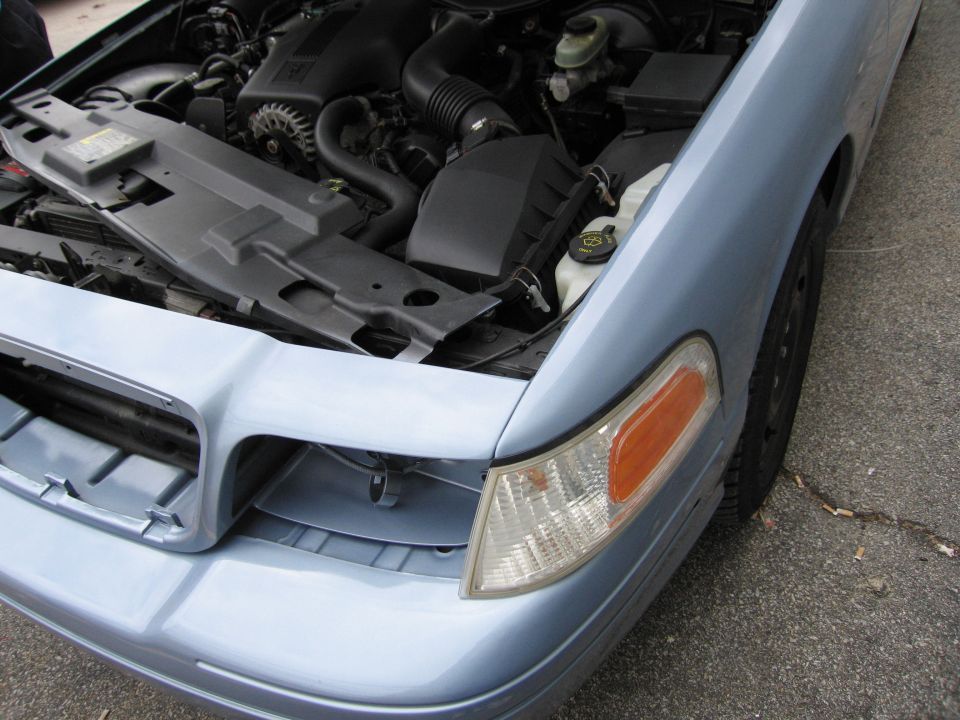 Light blue 2001 Ford Crown Victoria engine bay with hood open, showing engine components and front fender