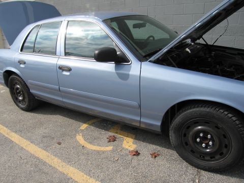 2001 Ford Crown Victoria - A light blue 2001 Ford Crown Victoria is parked with its hood and trunk open, revealing the engine and interior.