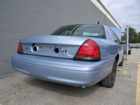 2001 Ford Crown Victoria - Rear view of a light blue 2001 Ford Crown Victoria parked outdoors, showing the taillights and bumper.